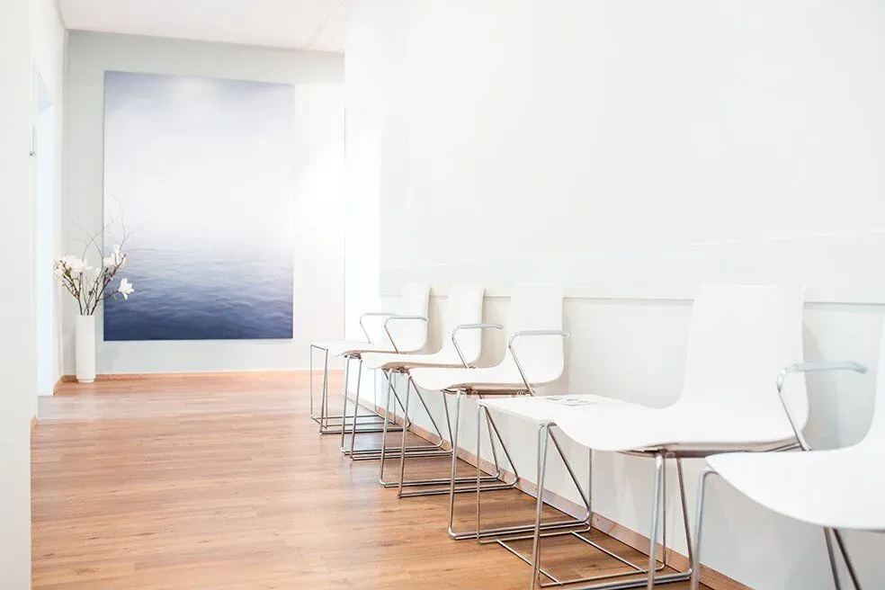 Wartezimmer mit weißen Stühlen und großem Meerbild