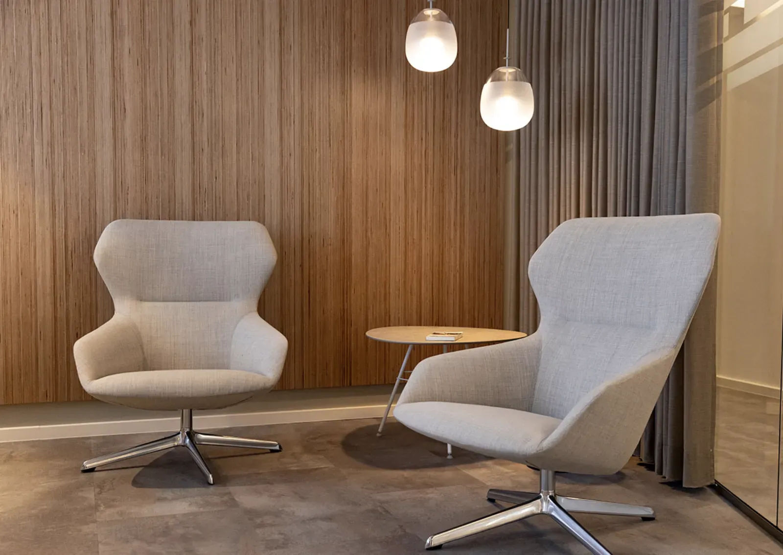 Lounge mit zwei Sesseln vor einer Holzwand