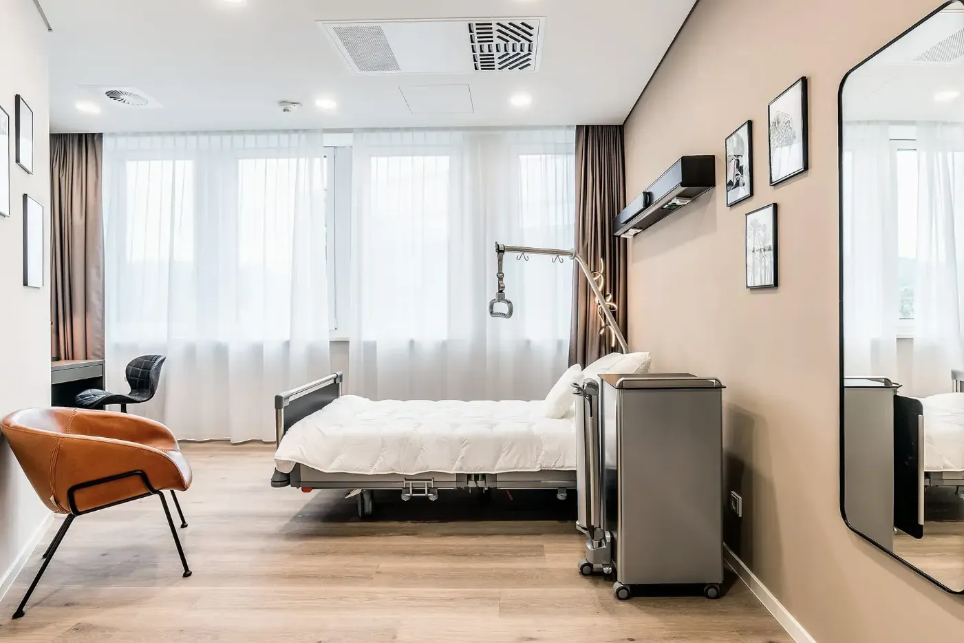Patientenzimmer mit Pflegebett, Sessel und Spiegel